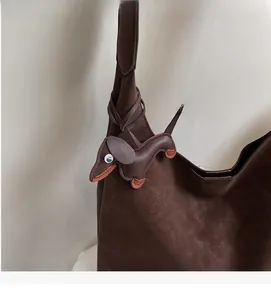 Detail of dark brown leather tote bag with a unique dachshund dog charm attachment