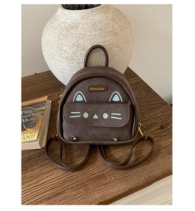 Detail view of mini brown faux suede backpack featuring a cute 3D cartoon cat design