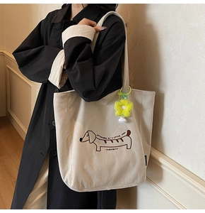 Close-up of beige corduroy tote bag featuring a cartoon dachshund and sunflower charm
