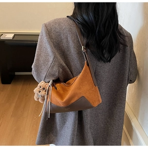 Detail der braunen Wildleder-Hobo-Tasche mit Lederbesatz und kleinem Teddybär-Anhänger