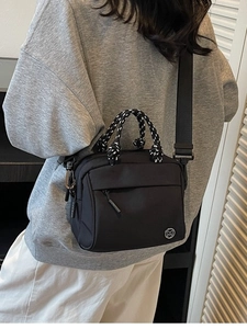 Minimalist black crossbody bag with striped rope handle and wide shoulder strap