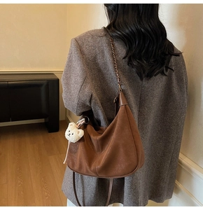 Brown faux leather crescent bag with chain strap and cute plush bear charm detail