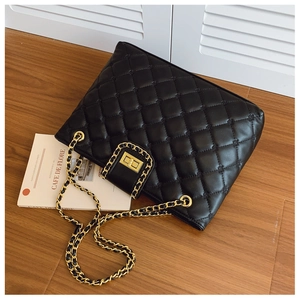 Détail du motif matelassé noir avec fermoir doré sur le sac à bandoulière en cuir