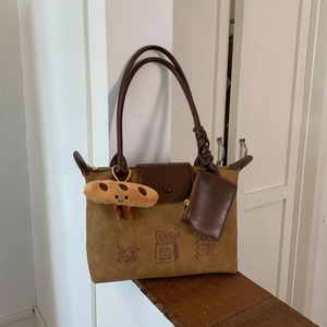 Close-up of khaki suede tote bag featuring brown leather flap and cute toast cartoon print