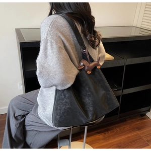 Detailed view of black textured tote bag with cute brown dachshund dog pendant accessory