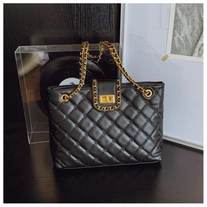 Détail du sac bandoulière matelassé noir avec chaîne dorée et fermoir métallique tournant