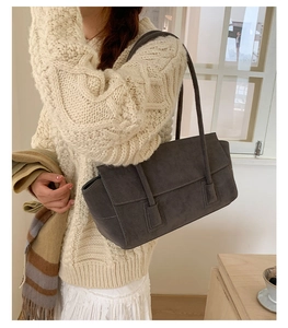 Detail of dark grey faux suede tote bag worn over the shoulder with cozy winter knitwear