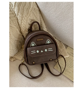 Close-up of cute cartoon cat embroidery and gold brand logo on brown mini backpack