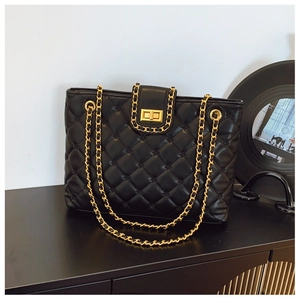Détail d'un grand sac cabas matelassé noir avec chaîne dorée et fermoir rotatif