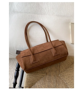 Detail shot of a brown suede shoulder bag featuring minimalist rectangular design and straps