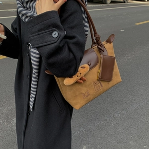Detail of camel suede tote bag with brown leather handle and mini purse charm