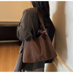 Detail of dark brown suede tote bag with a unique dachshund leather charm on strap
