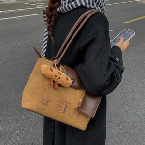 Detail of vintage brown suede tote bag featuring bread embroidery and plush charm