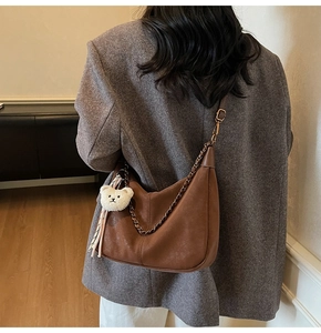 Brown leather Hobo bag with chain strap and plush bear charm shown on model
