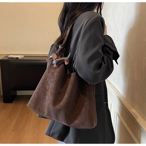 Detail of a dark brown suede tote bag featuring a cute dachshund puppy leather charm