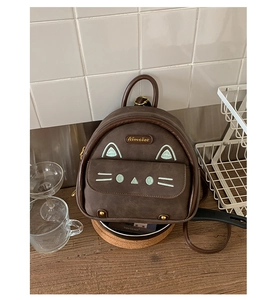 Detail of cute cat face embroidery on dark brown mini backpack with brand logo