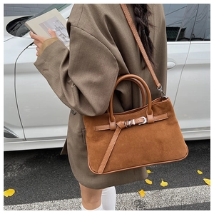 Close-up of caramel suede baguette bag with buckle detail and thin leather strap