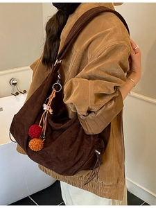 Retro dark brown corduroy hobo bag for women with decorative pompons worn by a model