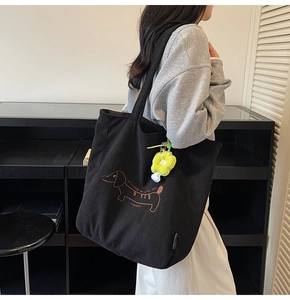 Detailed embroidery of a dachshund and a yellow flower plush charm on a black tote bag