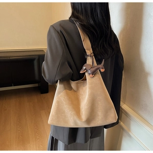 Detail of minimalist beige suede tote bag with brown dachshund leather charm accessory