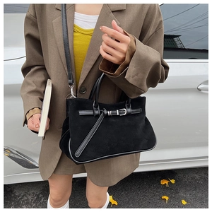 Fashionable black suede baguette bag with leather belt buckle shown in street style scene