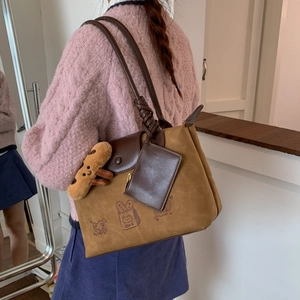 Detail showing vintage brown tote bag with cute cartoon bakery print and plush keychain