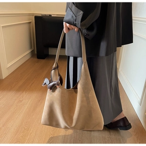 Detail of khaki suede tote bag featuring a cute dark brown dachshund leather charm