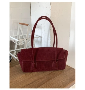 Detailed shot of the burgundy suede shoulder bag showing the premium texture and flap design