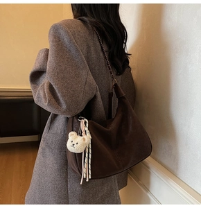 Detail of dark brown leather hobo bag with teddy charm and bronze chain strap