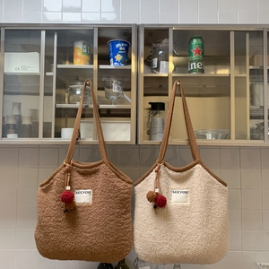 Detailed shot of plush faux shearling tote bags with woven handles and pom-pom charms