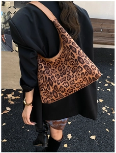 Detailed view of leopard print hobo bag with brown leather trim against autumn leaves