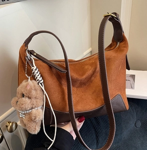 Detail der karamellfarbenen Wildledertasche mit Lederbesatz und Welpenanhänger
