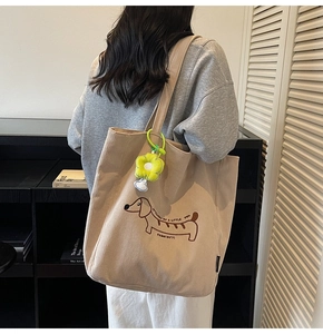 Detail of light brown corduroy tote bag featuring puppy embroidery and flower charm