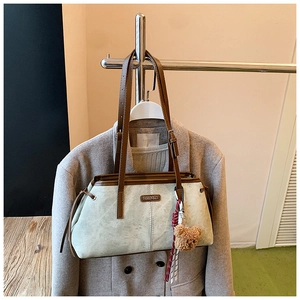 Détail du sac vert clair à texture marbrée avec breloque ours et sangle en cuir brun