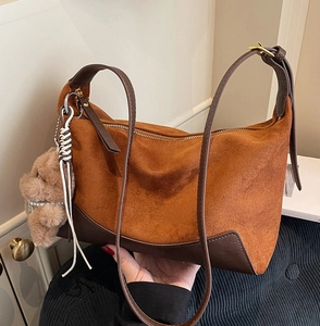 Detail der karamellfarbenen Suede-Tasche mit Lederboden und Plüschbär-Anhänger