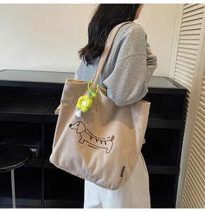Detail of beige corduroy tote bag with dachshund embroidery and sunflower pendant charm