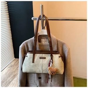 Détail du cabas rétro blanc cassé avec poignées brunes et pendentif ours en peluche