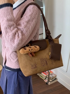 Brown suede tote bag with cartoon print and bread plush charm shown on model