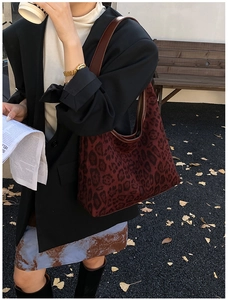 Detail of vintage leopard print hobo bag worn with black blazer in outdoor autumn setting