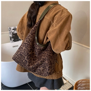 Detail of vintage leopard print tote bag with dark green leather strap on model