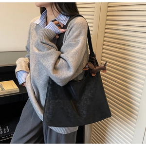 Detail of black matte hobo bag with a cute brown dachshund charm on a casual model
