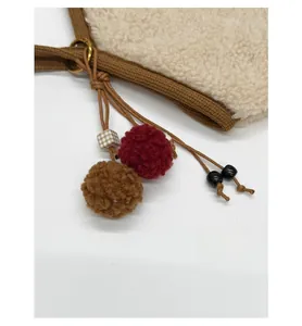 Detail of plush shearling shoulder bag with decorative colorful pom-pom charms