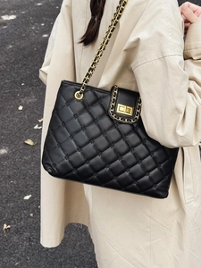 Sac à bandoulière matelassé noir avec chaîne dorée porté par un mannequin