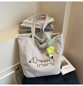 Close-up of beige corduroy tote bag with embroidered dog and yellow flower charm