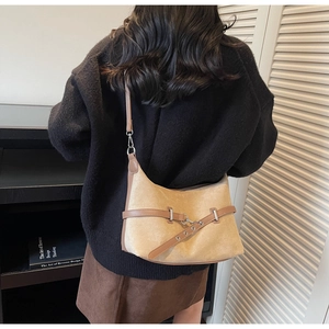 Modèle portant un sac demi-lune vintage en daim beige avec des détails en cuir marron