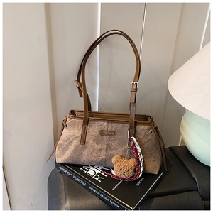 Détail du sac bandoulière marron vintage avec breloque ours en peluche et plaque mode