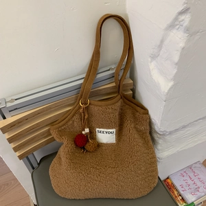 Detailed view of brown plush teddy tote bag with SEEYOU label and colorful fur pom-pom charm