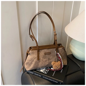 Détail du sac à bandoulière en cuir vintage marron avec breloque ours et logo en métal