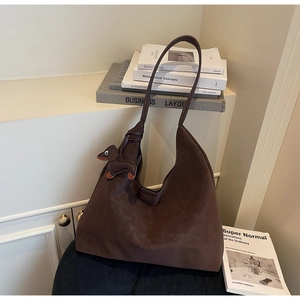 Close-up of textured dark brown tote bag with cute sausage dog leather pendant