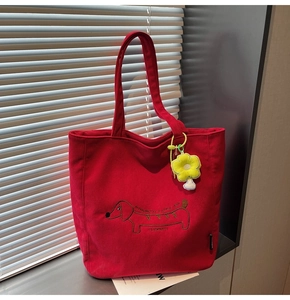 Detail of red corduroy tote bag with dachshund embroidery and yellow floral charm